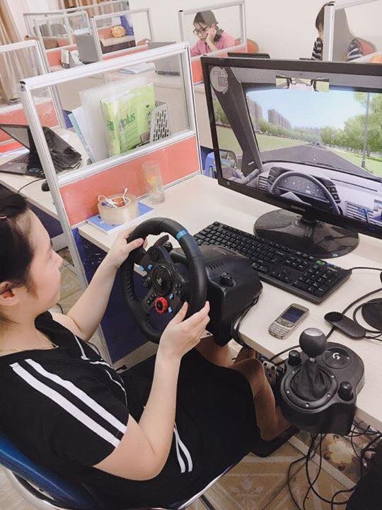 Học viên thực hành lái xe ô tô mô hình có vô lăng và bàn đạp chân ga phanh