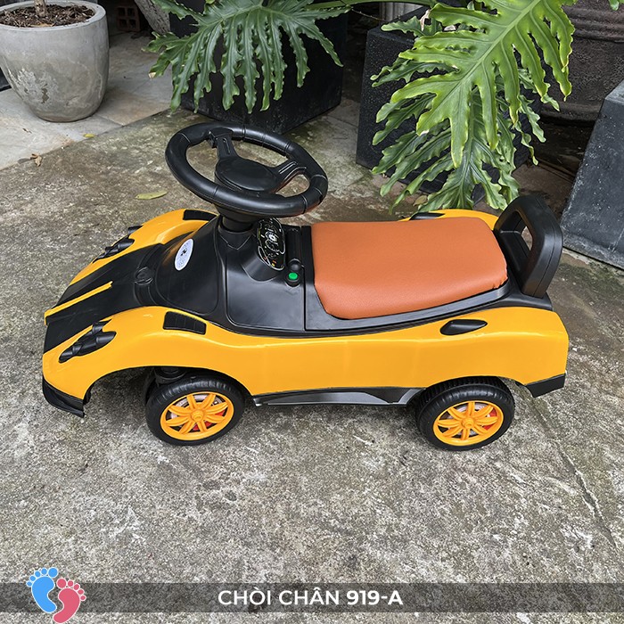 Bé trai ngồi trên xe chòi chân ô tô trong phòng