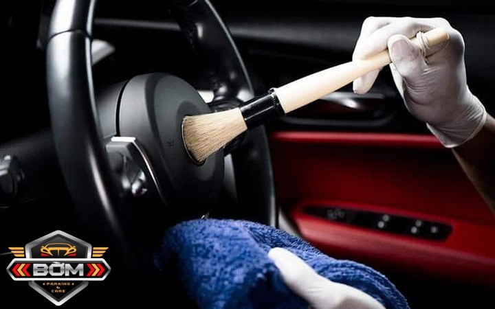 Chuyên viên bảo dưỡng nội thất xe ô tô đang làm sạch bảng điều khiển