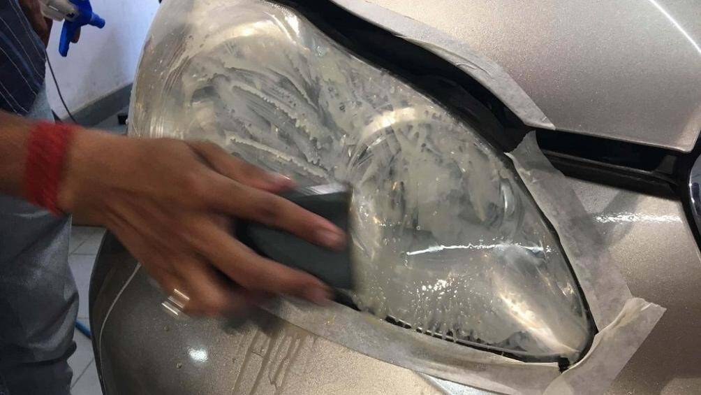 Thợ chuyên nghiệp đang phục hồi đèn pha xe ô tô bị vàng