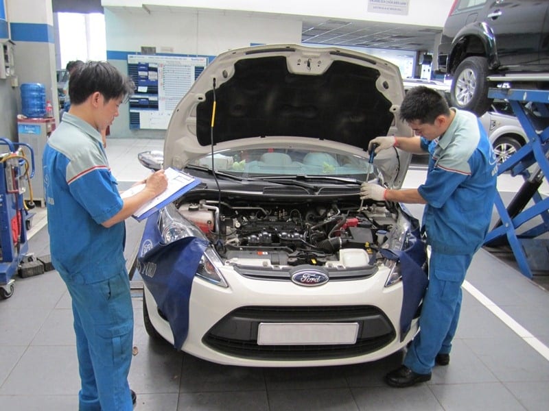 Kỹ thuật viên đang kiểm tra động cơ xe ô tô trước chuyến đi dài ngày