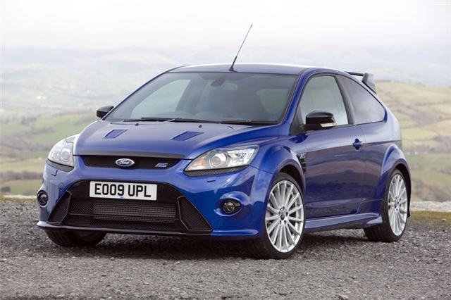 Một chiếc Ford Focus màu đỏ đời 2009-2011 đang di chuyển trên đường, thể hiện thiết kế mạnh mẽ, phù hợp làm xe ô tô cho sinh viên