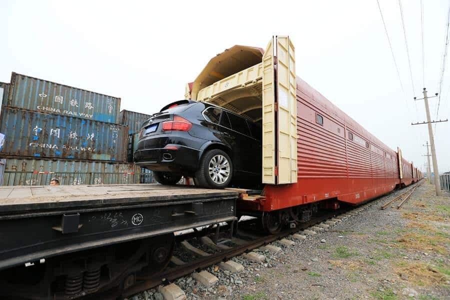 Một chiếc xe sedan màu trắng được đưa lên toa tàu hỏa chuyên dụng bằng cầu dẫn, chuẩn bị cho hành trình vận chuyển xe ô tô Hà Nội Huế an toàn.