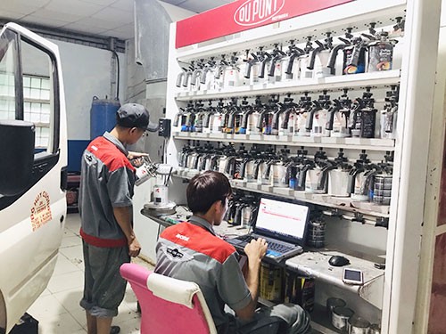 Kỹ thuật viên đang kiểm tra màu sơn xe ô tô bằng thiết bị chuyên dụng