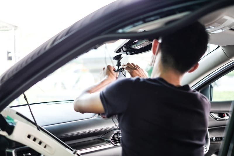 Thao tác lắp đặt camera hành trình lên kính lái xe ô tô, minh họa cách gắn thiết bị.