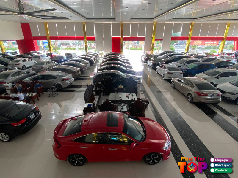 Nhân viên giới thiệu xe ô tô cũ cho khách hàng tại showroom