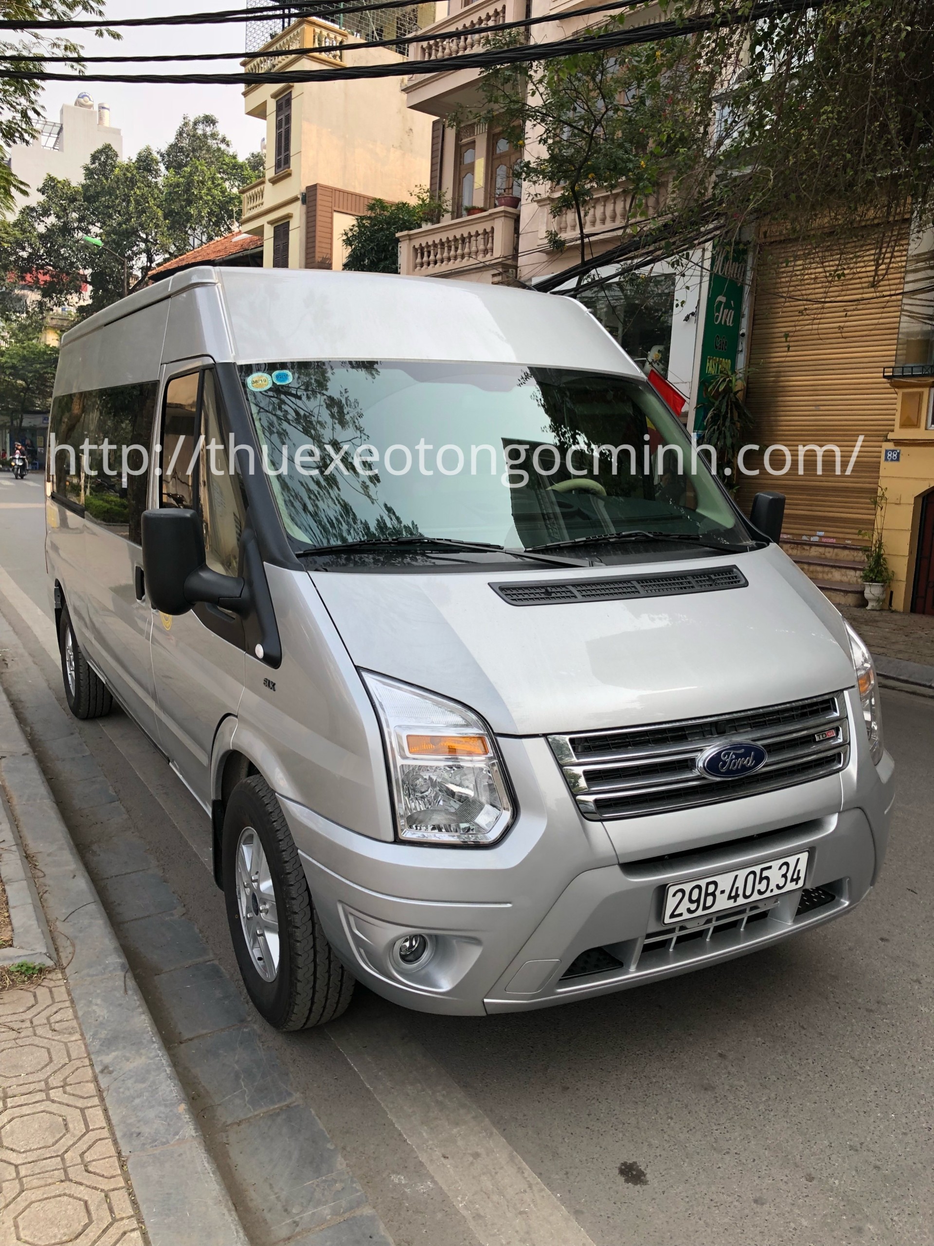 Xe Ford Transit 16 chỗ màu trắng đỗ trên đường