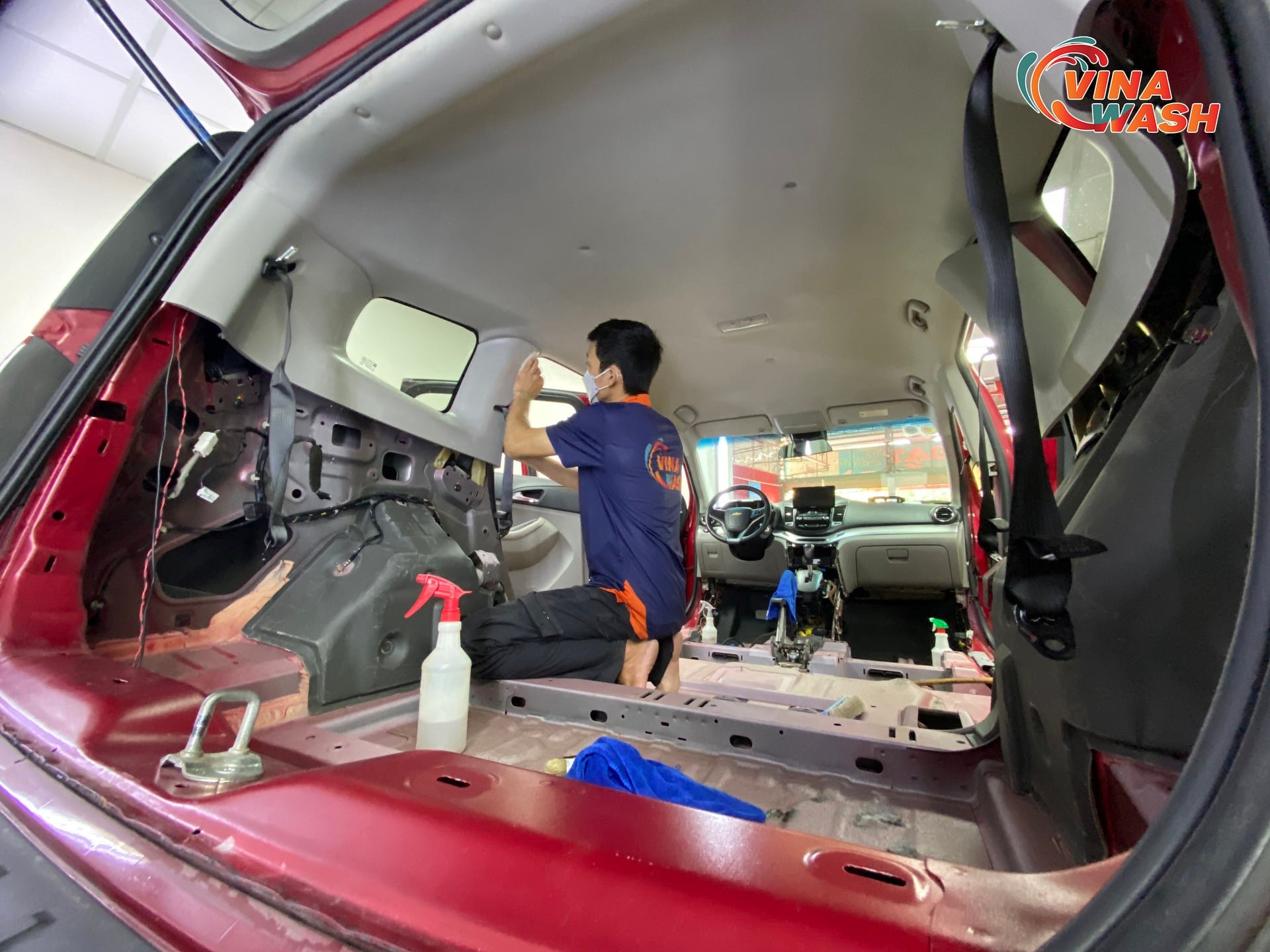 Kỹ thuật viên thực hiện vệ sinh nội thất xe ô tô chuyên sâu, tháo ghế để xử lý vết bẩn