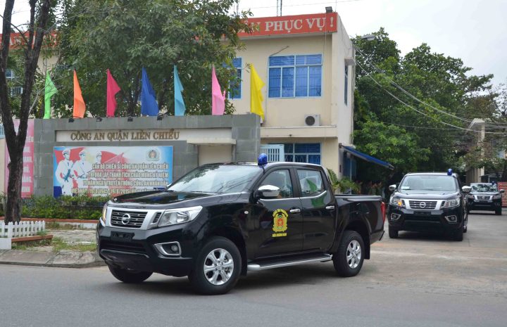 Xe công an chuyên dụng màu xanh cùng các sĩ quan đang thực hiện nhiệm vụ